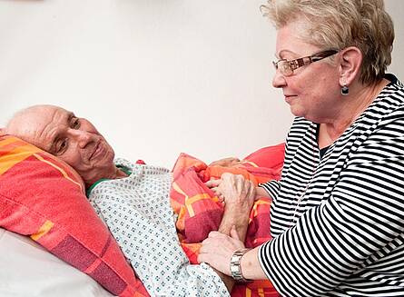Gut versorgt und medizinisch betreut am Lebensende Frau am Bett eines Schwerstkranken